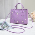 Elegant purple faux leather handbag with floral embroidery and gold hardware detail - Purple