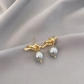 Goldene Knotenknoten-Ohrringe mit grauen Perlen auf weichem Seidenstoff präsentiert - Goldener Knoten Graue Perlenohrstecker