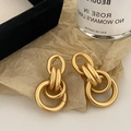 Detail van matgouden in elkaar grijpende ringoorbellen met een geborstelde metalen finish - Goud Mat