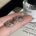 Vue rapprochée de boucles d'oreilles trèfle en argent et zircons sur fond élégant - Argenté