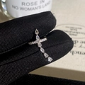 Dettaglio dell'anello a croce in argento con zirconi a goccia su guanto nero liscio - Ear Cuff a Croce Argentata (Placcato in Argento Vero)
