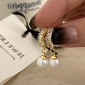 Vista macro de pendientes de perlas doradas con circonitas sobre tarjeta de joyas - Dorado