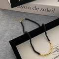 Gros plan des perles d'onyx noir et des cubes dorés sur un collier minimaliste - Collier / Doré