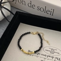 Détail du collier de perles noires avec accents dorés et fermoir mousqueton réglable - Bracelet / Doré