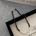 Détail d'un collier de perles en pierres noires avec cubes argentés sur un cadre - Collier / Argenté
