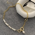 Elegante Goldkette mit Süßwasserperlen und strukturierten Rundanhängern auf grauem Leinen - Süßwasserperle - Vergoldetes Kupfer