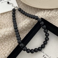 Vue détaillée du collier en pierres noires avec fermoir argenté sur tissu doux blanc - Collier en Pierre Naturelle 10mm