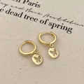 Elegante goldene Schmetterlingsohrringe mit Anhänger auf beigem Leinenhintergrund - Gold