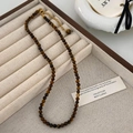 Detail of tiger eye stone necklace with gold lobster clasp on jewelry display tray - 4MM Bead Diameter / Brown