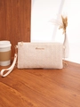 Dettaglio pochette intrecciata crema con scritta dorata su un tavolo di legno scuro - Bianco