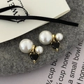 Detail of pink heart pearl earrings with gold metal accents on a grey felt surface - Black (Black Zirconia)