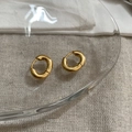 Close-up of matte gold chunky oval hoop earrings on a transparent glass tray - Gold Matte Hoop Earrings