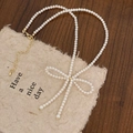 Elegant white pearl necklace with golden bow pendant on rustic paper background - White Pearl Bowknot Necklace B-26