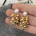 Dettaglio macro di orecchini vintage con perle bianche e sfere metalliche dorate lucide - Oro