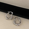 Macro view of silver twisted hoop earrings with a textured spiral design on a stand - Silver Twisted Hoop