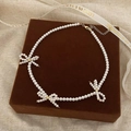 Detail view of pearl necklace with bow accents on a brown jewelry box display - Premium Simulated Pearl Bow Beaded Necklace