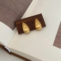 Detail of matte gold teardrop earrings with brushed metal texture on a wooden stand - Brushed Teardrop Earrings / Gold