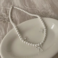Detailed close-up of pearl necklace with silver bow pendants on a ceramic plate - Pearl Silver Bowknot Pendant Necklace B-365