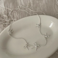 Detail of silver bow tassel necklace with pearls on a textured linen background - Silver Bowknot Rope Knot Necklace B-365