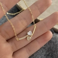 Detailaufnahme einer vergoldeten Halskette mit zwei Herzanhängern und klaren Zirkonia - Gold Herz