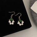 Dettaglio di orecchini dorati con perle verde smeraldo e perle barocche su velluto nero - Orecchini in Pietra Naturale Verde Smeraldo
