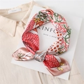 Close-up of a printed silk scarf tied as a bow on a white magazine with a beige shirt - Brown