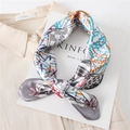Close-up of printed satin silk scarf with geometric patterns and bow detail on a book - 60x60cm / Grey Modern Print (FL21-6)
