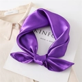Close-up of a glossy purple silk square scarf tied in a bow on a beige shirt - Purple