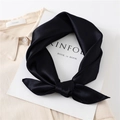 Close-up of black satin silk scarf tied in a bow on a beige shirt collar - Black