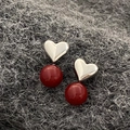 Close-up of red pearl heart earrings featuring silver accents on a textured wool background - Red Pearl Silver Heart Earrings