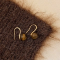 Macro detail of golden ear hooks with brown tiger eye stone beads on plush fabric - 8mm Tiger's Eye Ear Hook
