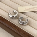 Detail of silver C-shaped double-layer hoop earrings with woven texture on a beige tray - Real Gold Plated Silver