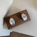 Detail of matte silver oval earrings with brushed texture on walnut display board - Silver Brushed Style