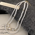Detail van dubbele zoetwaterparelketting met barokke hanger en gouden metalen sluiting - Hoogglans Zoetwaterparel Stijl