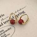 Detail of vintage gold earrings with deep red beads and pearls on textured fabric - Red Agate