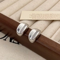 Macro shot of polished silver bean earrings on vintage velvet display box for women - Silver