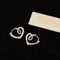 Macro-opname van zilveren hartvormige oorringen met gepolijste afwerking op zwart fluweel - Zilveren hart knoop oorklikker