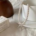 Détail d'un collier de perles avec pendentif nœud suspendu sur une tasse en porcelaine - Style Noeud Argenté (B-377)