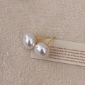 Nahaufnahme eleganter weißer Perlenohrstecker mit S925 Silberstiften auf beigem Hintergrund - 14mm / 14mm Weiße Runde Perlenohrstecker