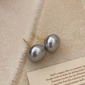 Detail of grey pearl studs with gold posts on a beige textured fabric background - 14mm Grey Pearl Stud Earrings
