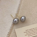 Close-up of vintage grey pearl stud earrings with gold pins on elegant textured fabric - 10mm Grey Pearl Stud Earrings