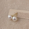 Detalle de pendientes de perlas púrpuras con pernos dorados sobre fondo beige texturizado - 10mm