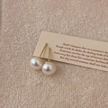 Primer plano de pendientes de perlas luminiscentes con postes dorados sobre un fondo beige - 8mm