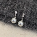 Dettaglio di orecchini d'argento con zircone e grande perla grigia su sfondo in tessuto - Argento Perla Grigia