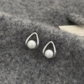 Primer plano de pendientes de gota plateados con perlas blancas y fondo gris - Pendientes de perlas blancas con marco de lágrima plateado (A-663)