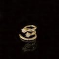 Makroaufnahme von goldenem Spiral-Ohrclip mit funkelnden Zirkonen und Sternendetails auf Schwarz - Mikro-gesetzte Zirkonia Stern Ohrmanschette / Gold
