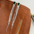 Detail of silver tassel earrings with a rectangular emerald stone and fine snake chains - Emerald Green Zirconia Silver Tone Earrings