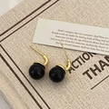 Detailed view of vintage gold stud earrings with large black spherical beads on poetry card - Gold Black Pearl Hook