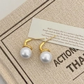 Detail shot of elegant gold hook pearl earrings resting on a vintage script card - Gold White Pearl Hook