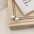 Close-up of classic round white pearl earrings on a book with soft natural lighting - 8mm Shell Pearl Stud